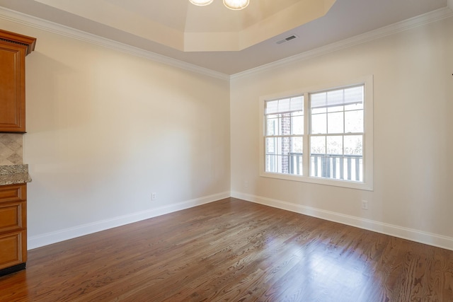 spare room featuring ornamental molding, dark hardwood / wood-style floors, and a raised ceiling