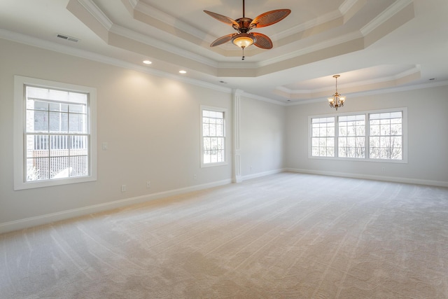 spare room with ceiling fan with notable chandelier, ornamental molding, light colored carpet, and a raised ceiling