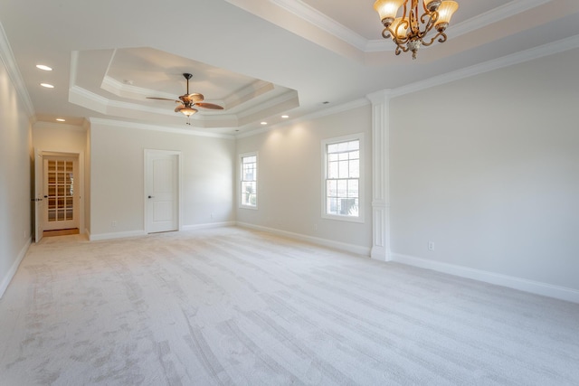 carpeted empty room with ornamental molding, ceiling fan with notable chandelier, and a tray ceiling