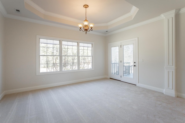 carpeted spare room with an inviting chandelier, ornamental molding, and a tray ceiling