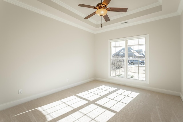 carpeted spare room with ceiling fan, ornamental molding, and a raised ceiling