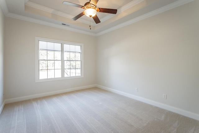 carpeted spare room featuring a tray ceiling, ornamental molding, and ceiling fan