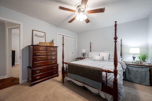 bedroom featuring ceiling fan, a textured ceiling, a closet, and light colored carpet