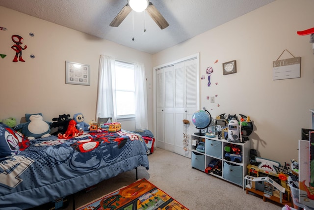 bedroom featuring ceiling fan, light colored carpet, a textured ceiling, and a closet