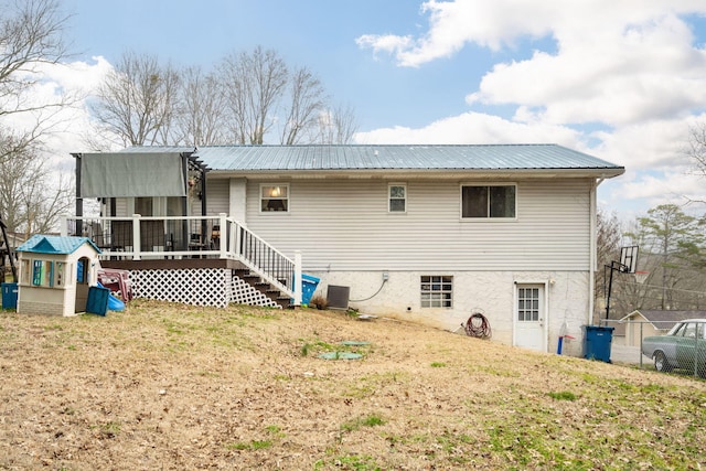 back of house featuring central AC, a wooden deck, a playground, and a lawn