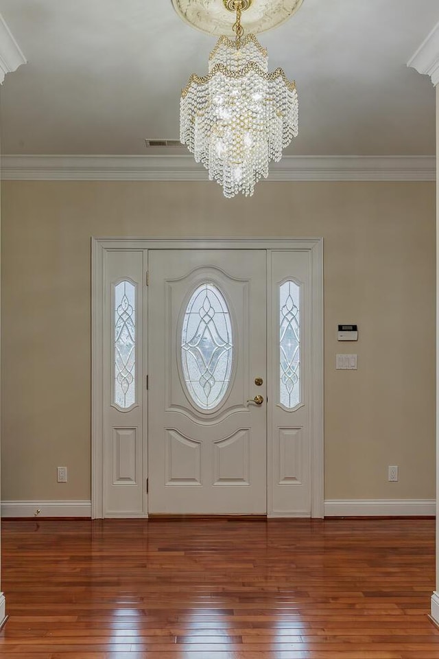 entrance foyer featuring ornamental molding, hardwood / wood-style floors, and a chandelier