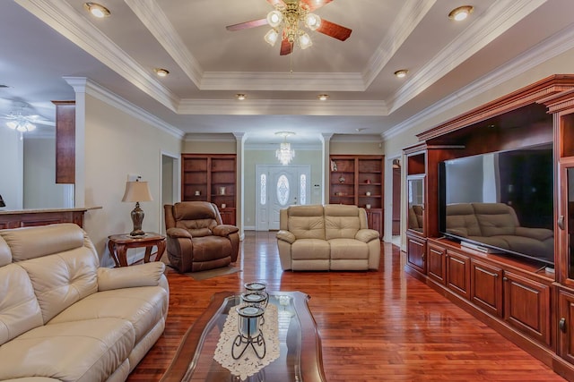 living room with hardwood / wood-style floors, ceiling fan, a raised ceiling, crown molding, and built in shelves