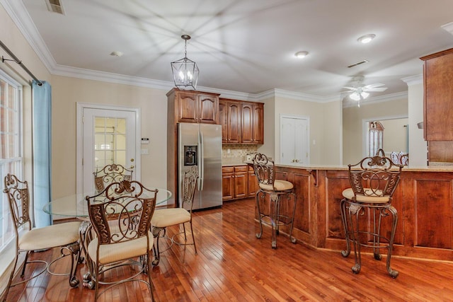 kitchen featuring stainless steel refrigerator with ice dispenser, dark hardwood / wood-style floors, a kitchen breakfast bar, kitchen peninsula, and pendant lighting