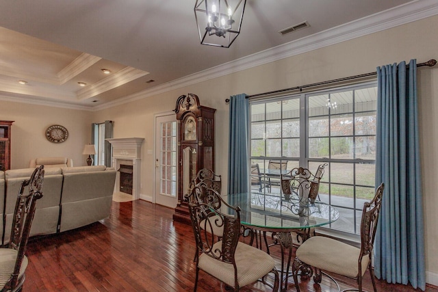 dining area with crown molding, a tray ceiling, dark hardwood / wood-style floors, and a chandelier