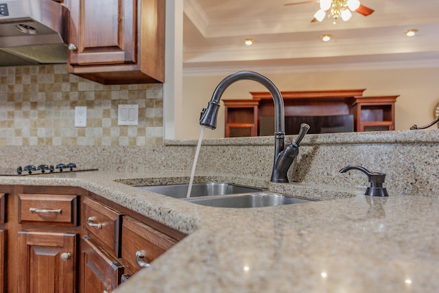 kitchen with extractor fan, sink, backsplash, ornamental molding, and light stone countertops