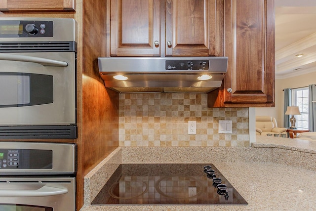 kitchen featuring black electric cooktop, backsplash, exhaust hood, and oven