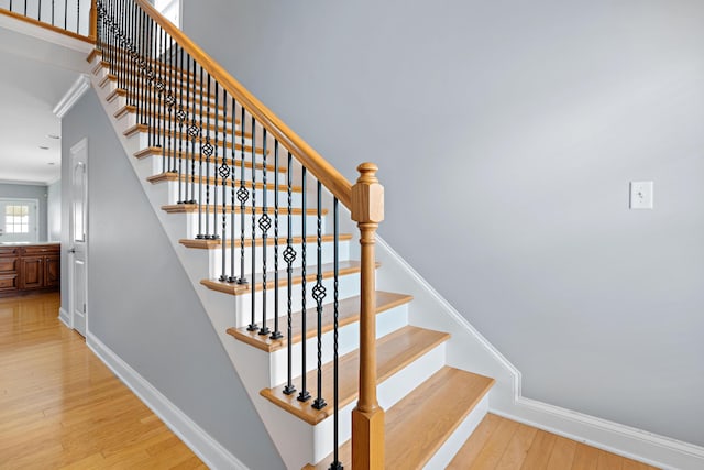 staircase with crown molding and wood-type flooring