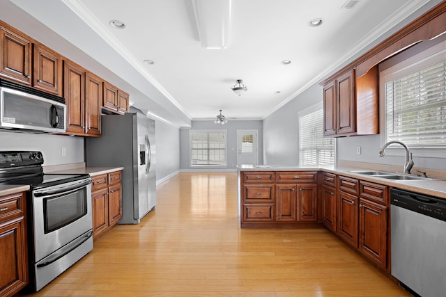 kitchen featuring sink, stainless steel appliances, ornamental molding, kitchen peninsula, and light wood-type flooring