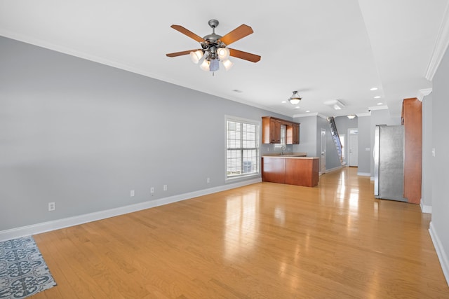 unfurnished living room featuring ornamental molding, ceiling fan, and light hardwood / wood-style floors