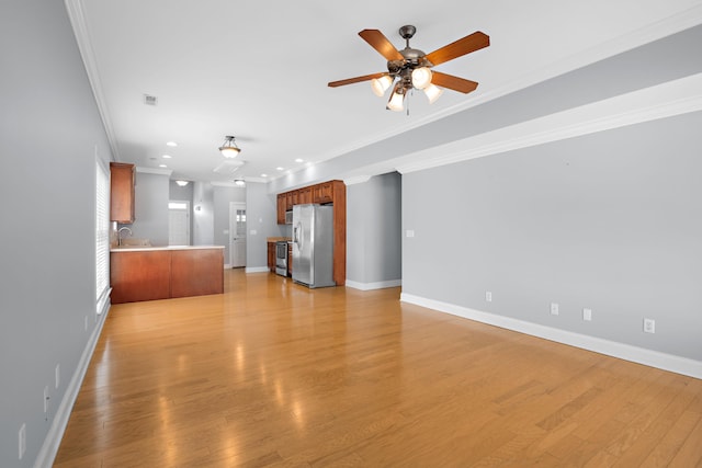 unfurnished living room featuring ornamental molding, sink, ceiling fan, and light hardwood / wood-style flooring