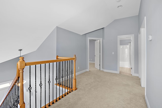 hall with vaulted ceiling and light colored carpet