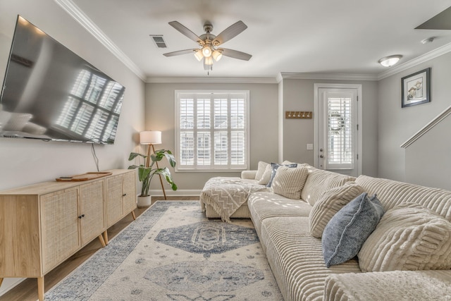 living room with wood-type flooring, ornamental molding, and ceiling fan