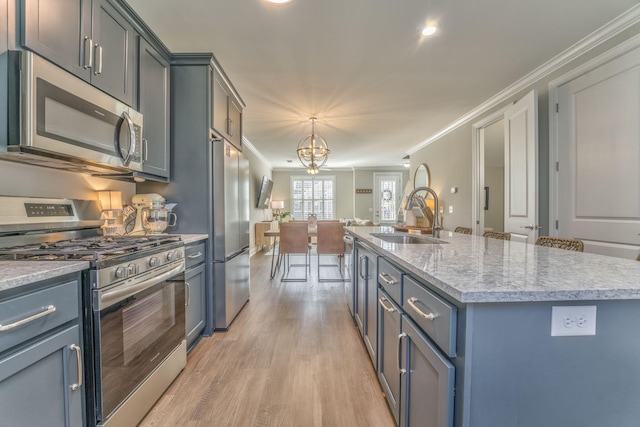 kitchen featuring sink, crown molding, a center island with sink, and appliances with stainless steel finishes