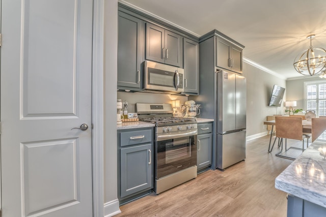 kitchen with an inviting chandelier, decorative light fixtures, ornamental molding, appliances with stainless steel finishes, and gray cabinets