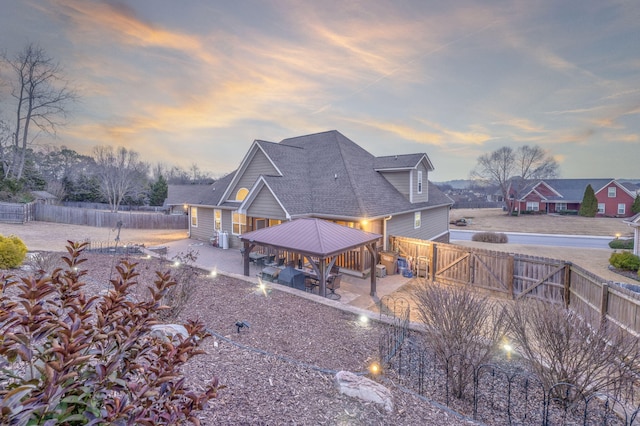 back house at dusk with a gazebo and a patio