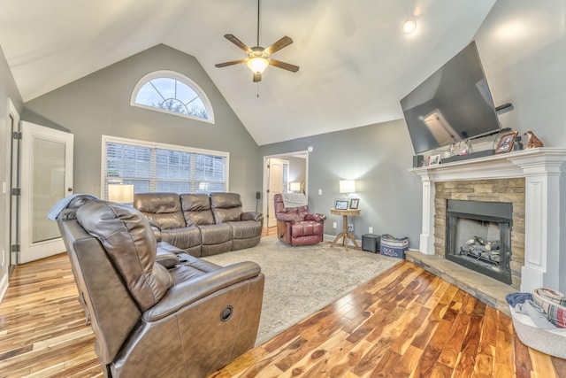 living room with ceiling fan, high vaulted ceiling, a fireplace, and light hardwood / wood-style flooring