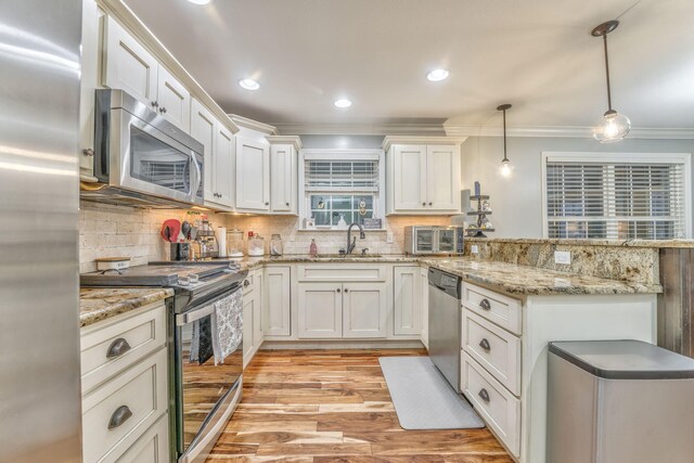 kitchen featuring pendant lighting, stainless steel appliances, and white cabinets