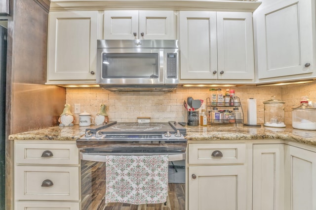 kitchen with tasteful backsplash, appliances with stainless steel finishes, hardwood / wood-style floors, and light stone counters