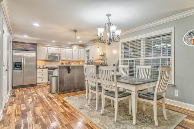 dining space with crown molding, an inviting chandelier, and light hardwood / wood-style floors