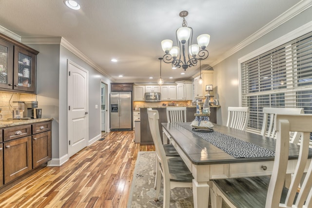 dining area featuring ornamental molding, hardwood / wood-style floors, and a notable chandelier