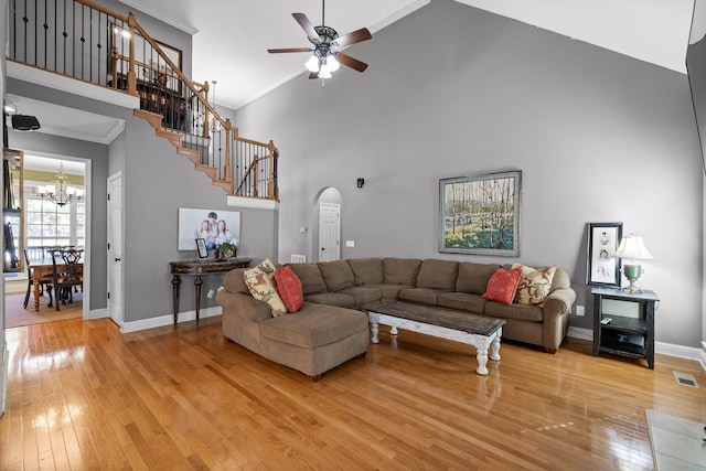 living room featuring hardwood / wood-style flooring, crown molding, ceiling fan with notable chandelier, and high vaulted ceiling