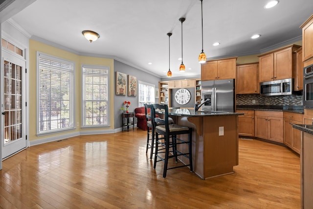 kitchen with pendant lighting, crown molding, a breakfast bar area, stainless steel appliances, and a kitchen island