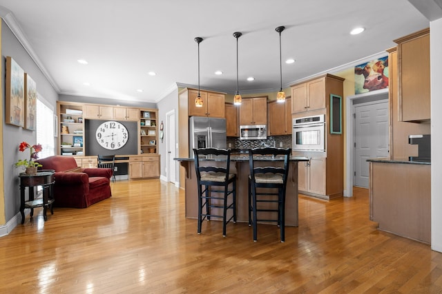 kitchen with hanging light fixtures, stainless steel appliances, a breakfast bar, and light wood-type flooring