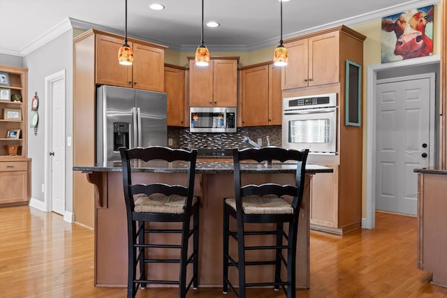 kitchen featuring stainless steel appliances, a kitchen island, a breakfast bar, and hanging light fixtures