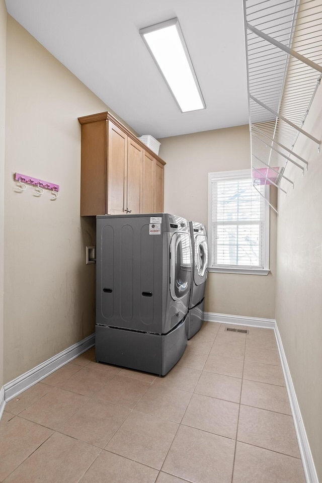 laundry area featuring cabinets, washing machine and dryer, and light tile patterned floors