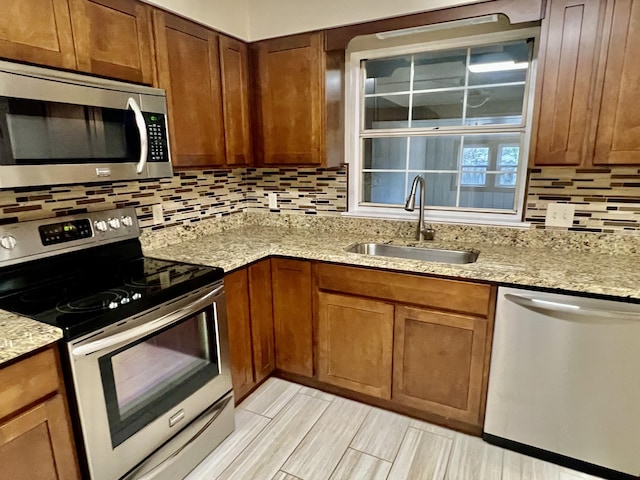 kitchen featuring appliances with stainless steel finishes, sink, backsplash, and light stone counters