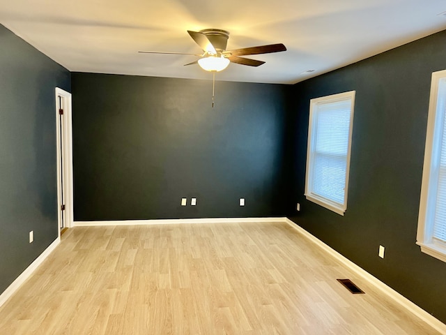 empty room featuring ceiling fan, plenty of natural light, and light wood-type flooring