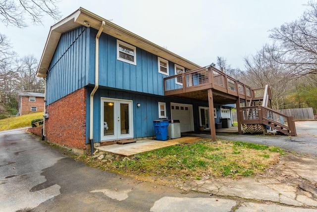 rear view of house featuring french doors, a garage, and a deck