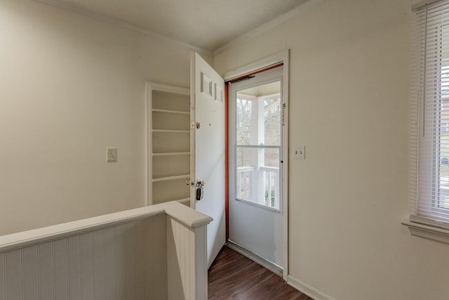 doorway with dark hardwood / wood-style flooring, crown molding, and a healthy amount of sunlight