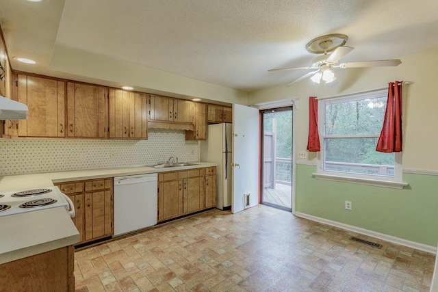 kitchen with sink, white appliances, ceiling fan, backsplash, and a textured ceiling