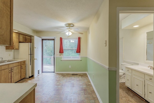 kitchen with ceiling fan, sink, decorative backsplash, and a textured ceiling