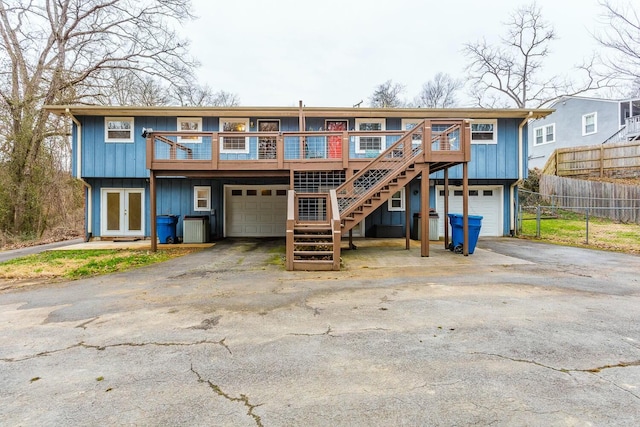 rear view of house featuring a wooden deck, a garage, central AC, and french doors