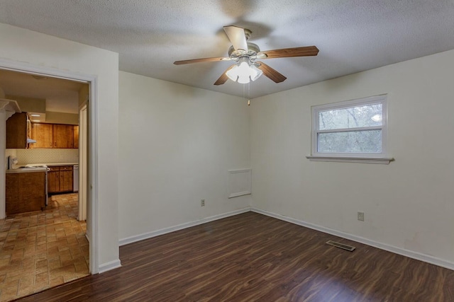 empty room with ceiling fan, dark hardwood / wood-style floors, and a textured ceiling