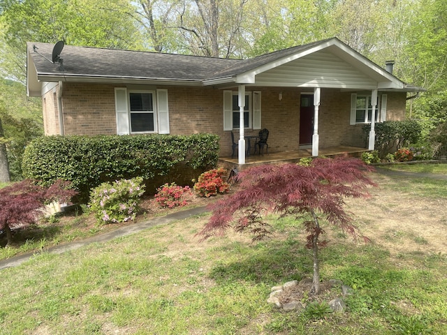 single story home featuring a porch, brick siding, and a front yard