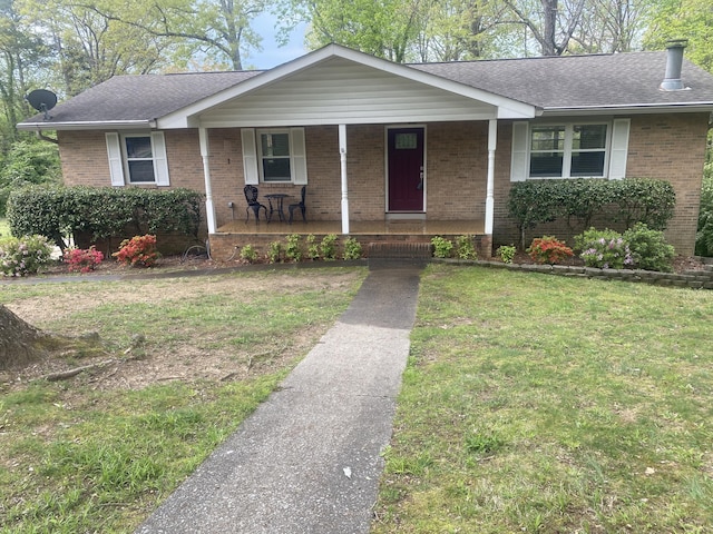 single story home with a porch, brick siding, a shingled roof, and a front lawn