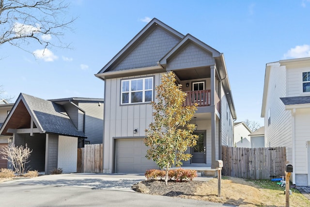 view of front of home with an attached garage, a balcony, fence, concrete driveway, and board and batten siding