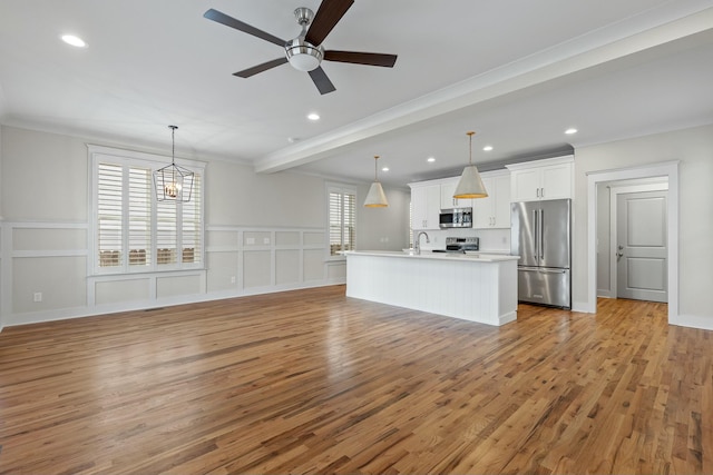 kitchen with stainless steel appliances, light countertops, light wood-type flooring, white cabinetry, and a sink