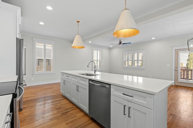 kitchen featuring stainless steel appliances, a sink, a healthy amount of sunlight, ornamental molding, and light wood-type flooring