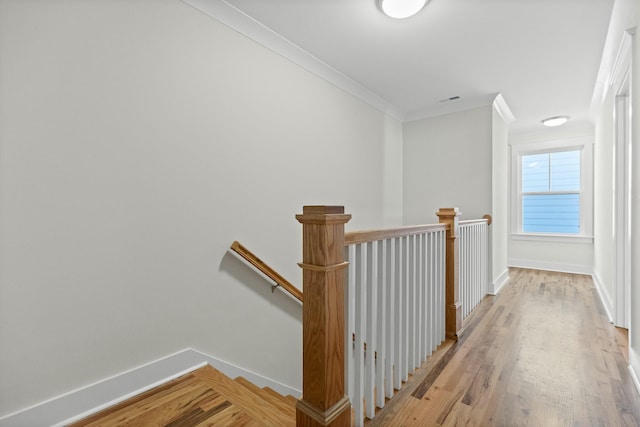 corridor with ornamental molding and light hardwood / wood-style floors