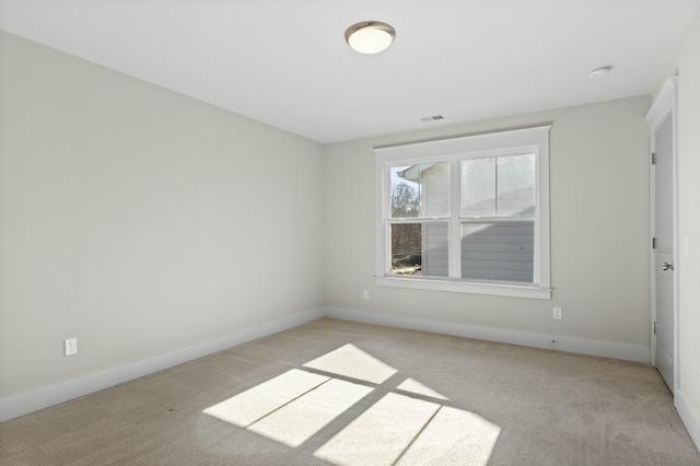 empty room with baseboards, visible vents, and light colored carpet