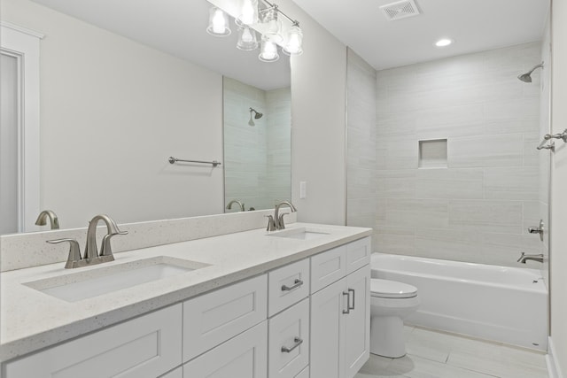 bathroom featuring visible vents, a sink, tiled shower / bath, and toilet